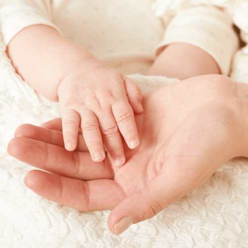 A baby holding a mothers hand as a result of reflexology fertility treatment